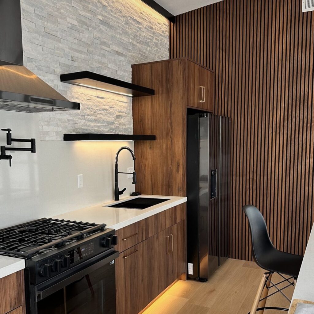 Modern kitchen with a vertical wood slat accent wall and stone textures.