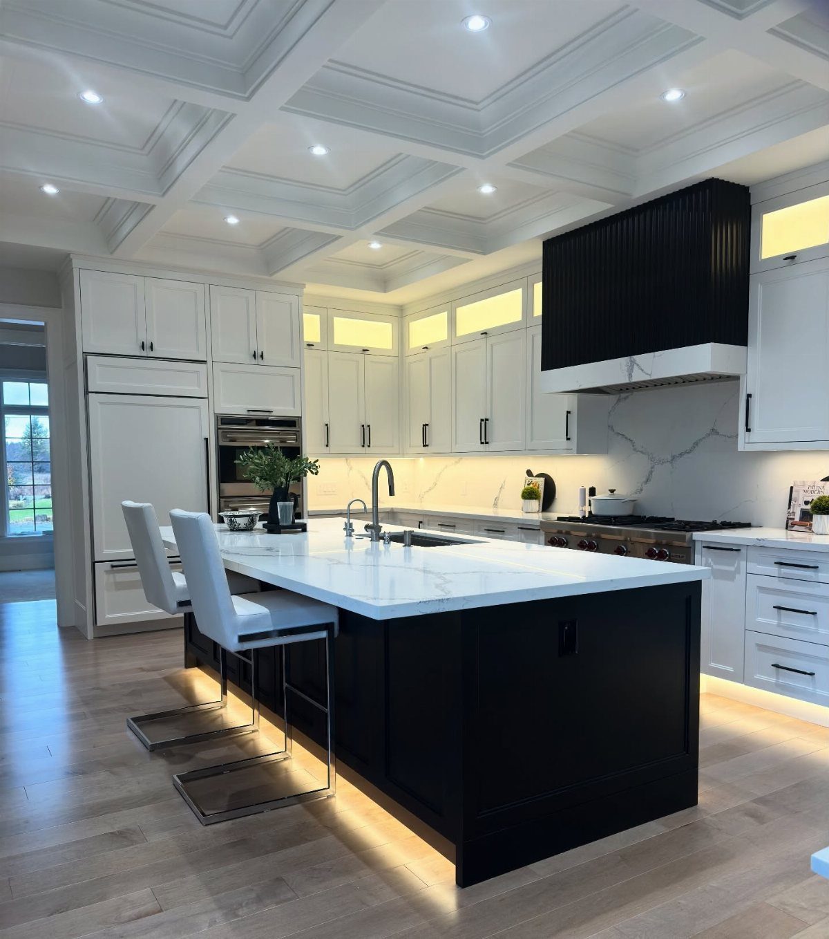 Modern kitchen with white upper cabinets and a large black island with marble top.