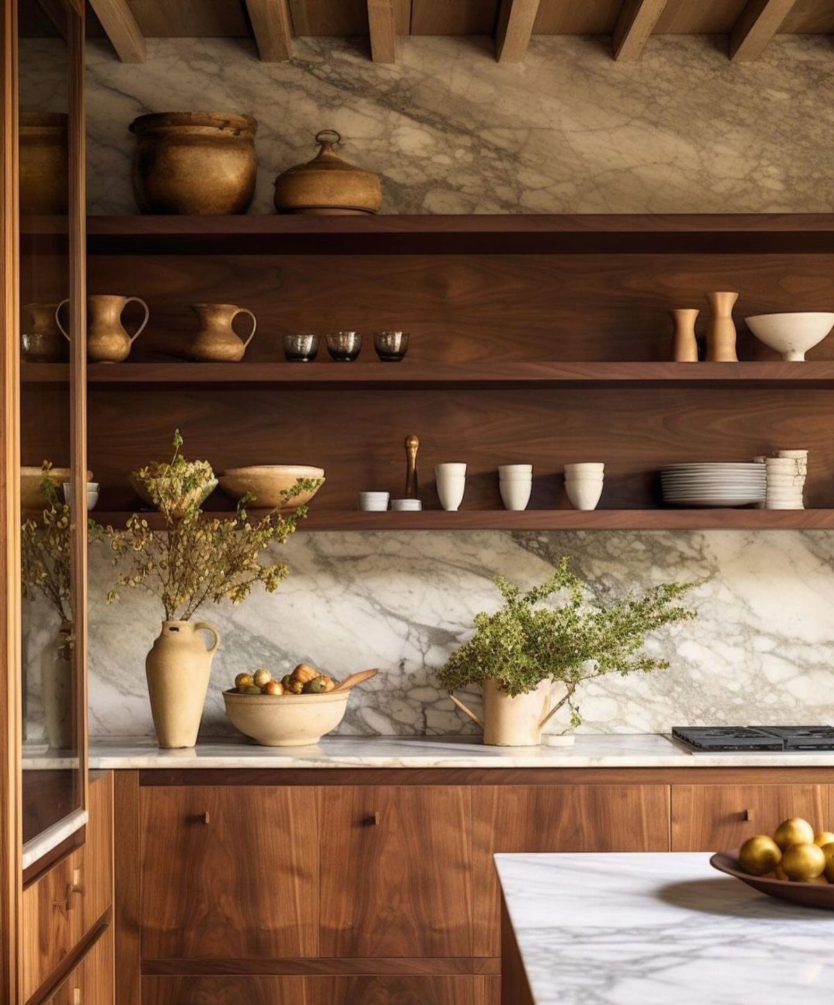 Dark wood open shelves with ceramic pottery against a marble kitchen wall.