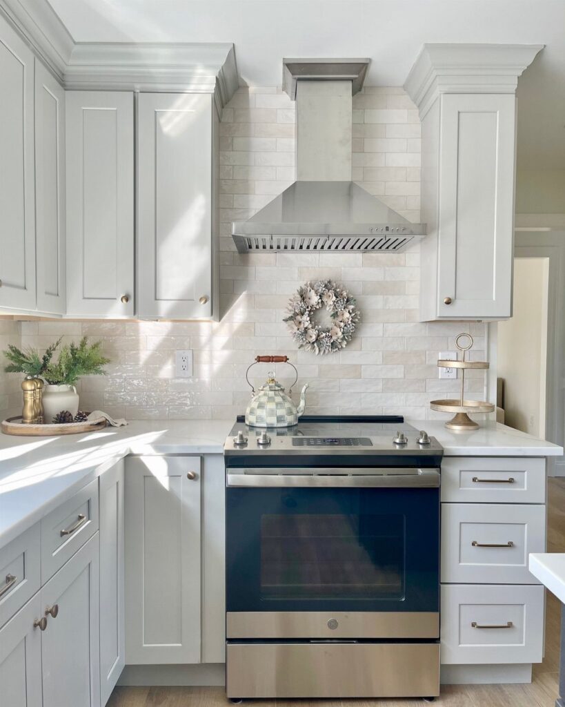White kitchen cabinets and countertops with a light tiled backsplash and stainless steel appliances.