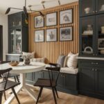 Dark green built-in banquette with storage drawers and a white round dining table.