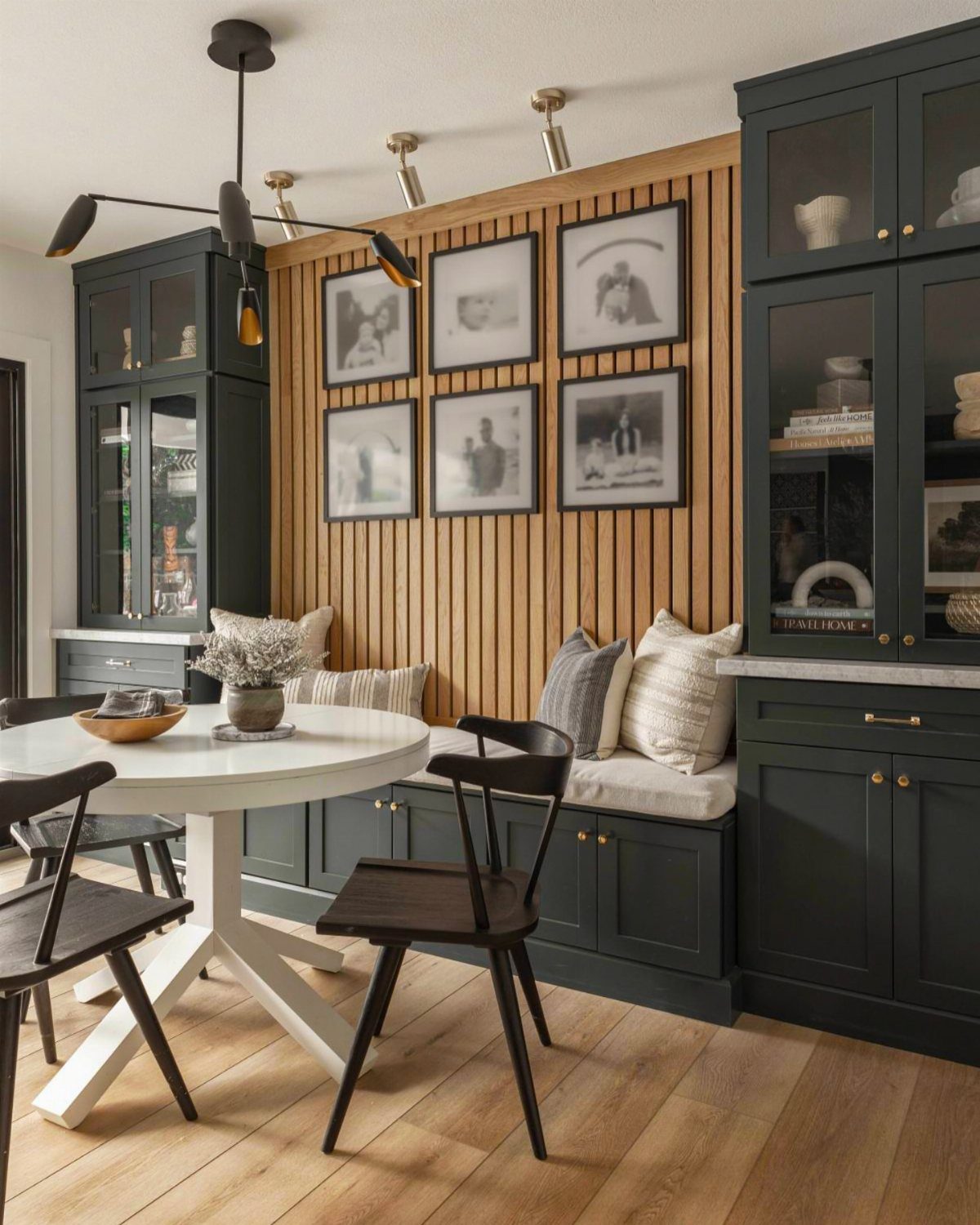Dark green built-in banquette with storage drawers and a white round dining table.
