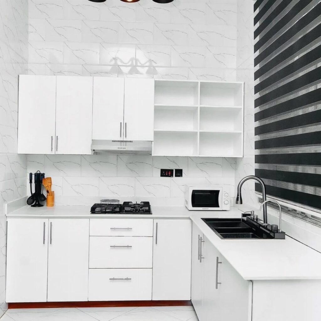 White kitchen cabinets and countertops with a patterned white tile backsplash and black accents.