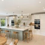 Modern kitchen with white cabinets and a light-green island with wooden stools.