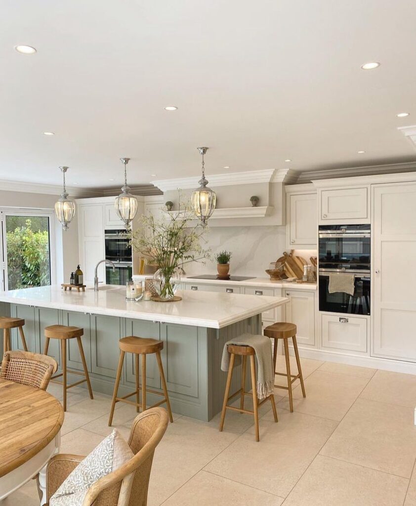 Modern kitchen with white cabinets and a light-green island with wooden stools.