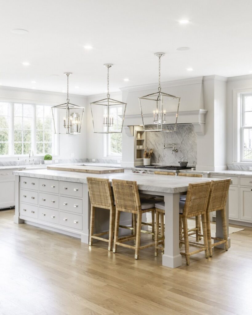 White kitchen island with a light countertop and four woven wicker bar stools.