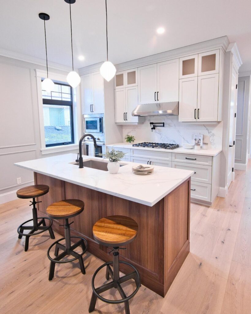 Wooden kitchen island with white countertop, integrated sink, and three wooden bar stools.