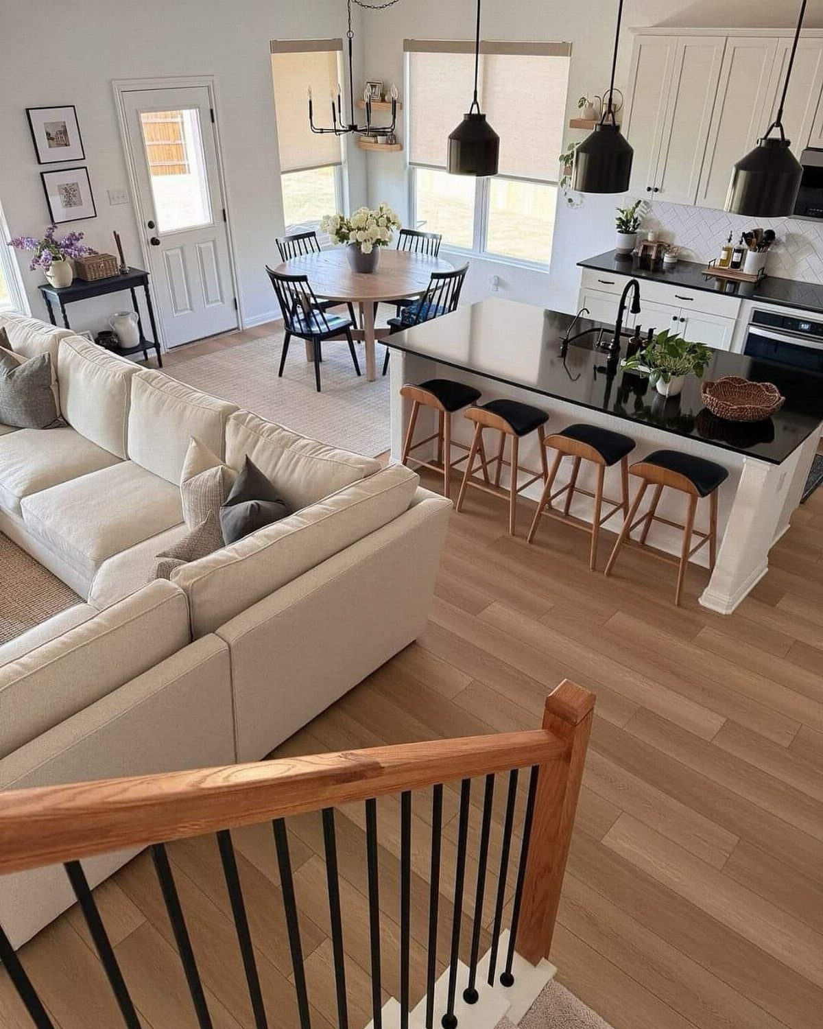 Open concept living area with white sofa, dining set, and modern black kitchen.