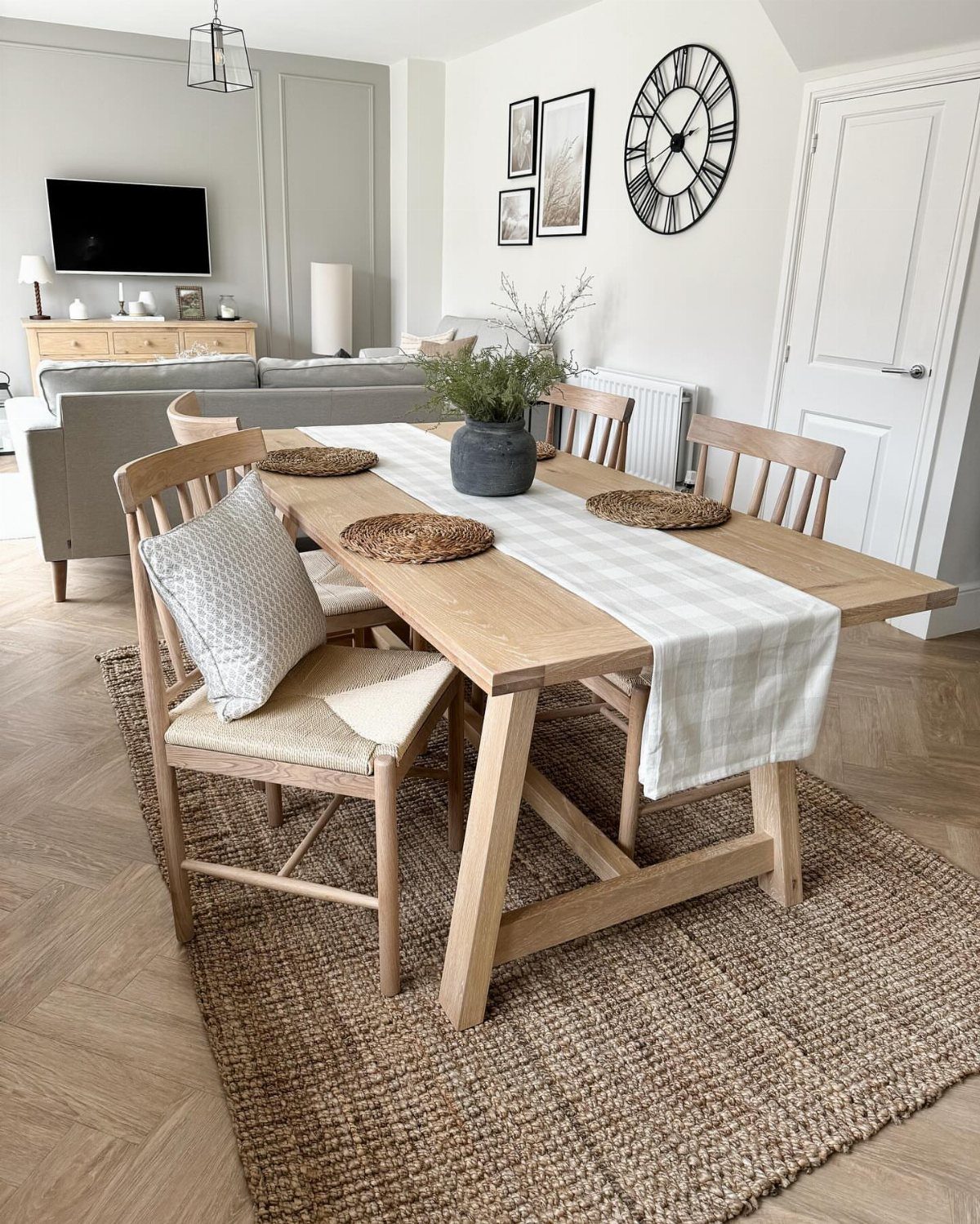 Wooden dining table with chairs and a white runner on a brown jute rug