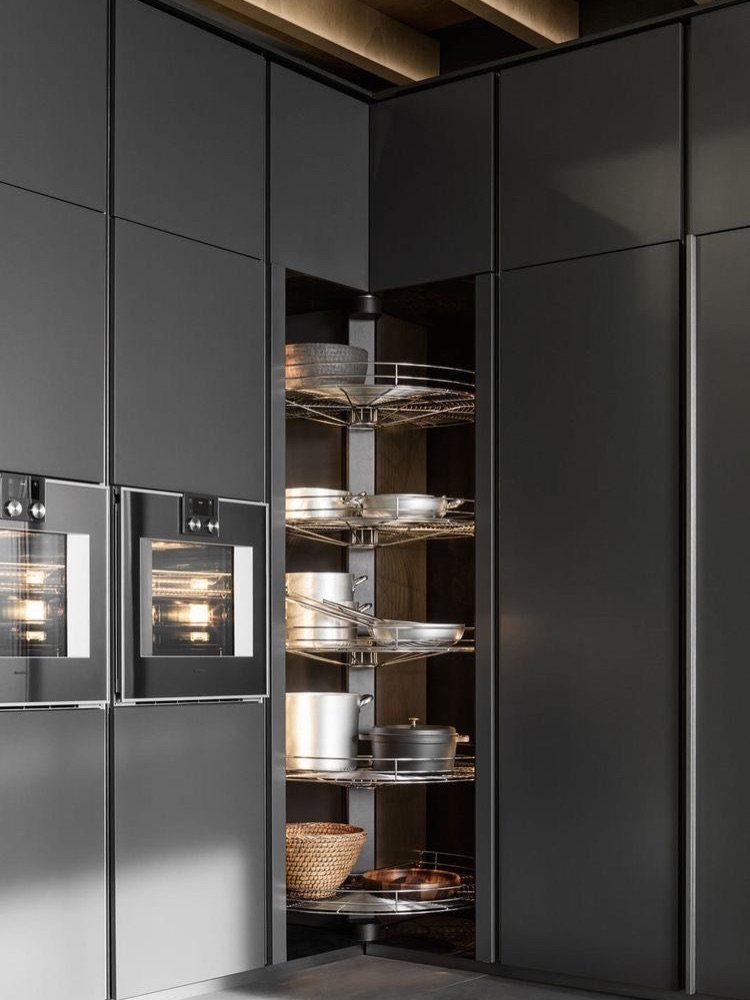 Dark grey kitchen cabinets with an open corner carousel shelf holding cookware.