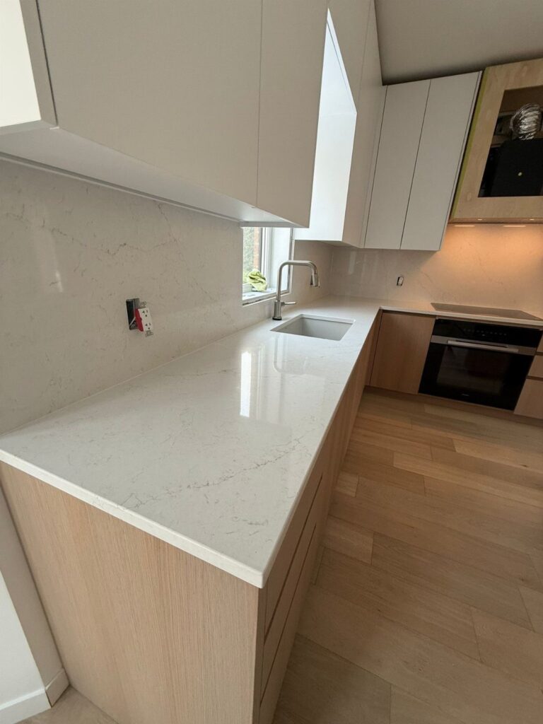 White quartz countertops with grey veining in a modern kitchen with wood cabinets.