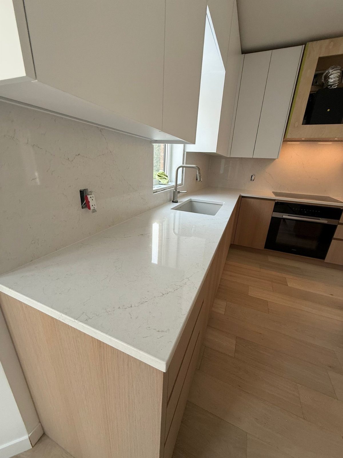 White quartz countertops with grey veining in a modern kitchen with wood cabinets.