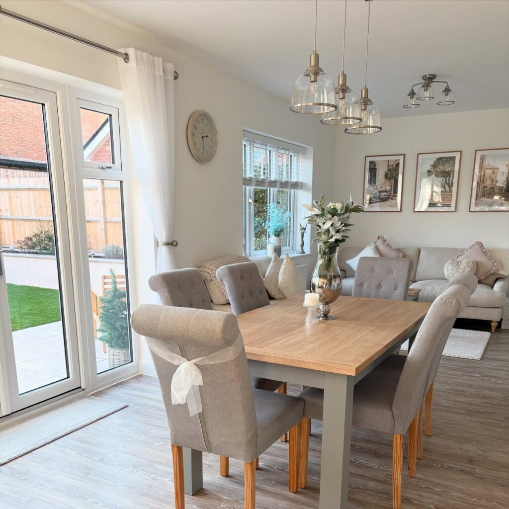 Three glass pendant lights hanging over a wooden dining table with grey chairs.