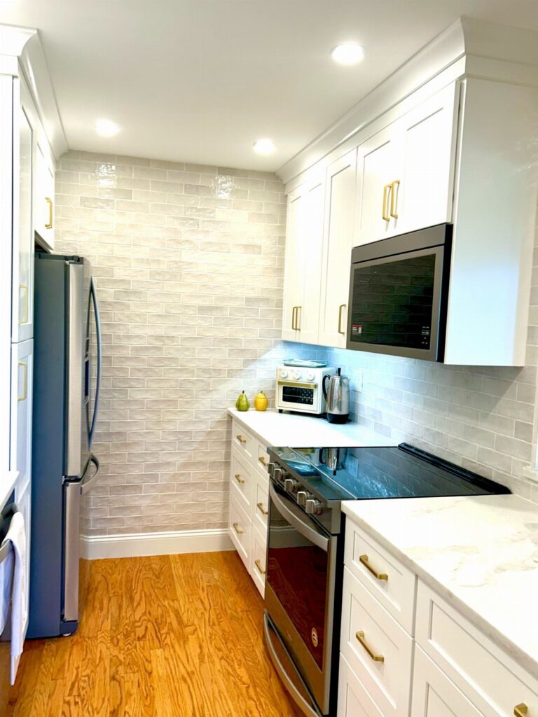 Galley kitchen with white cabinetry, recessed ceiling lights, and under-cabinet lighting.