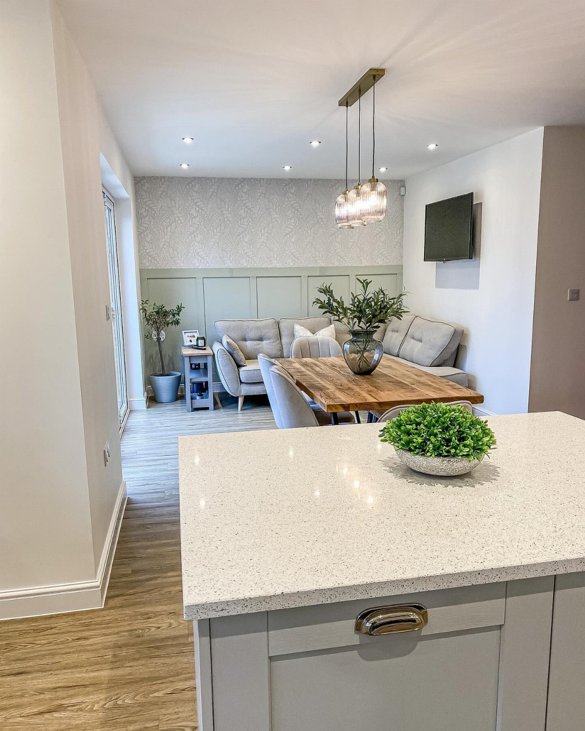 White quartz kitchen island overlooking a living room with a grey sofa and table.