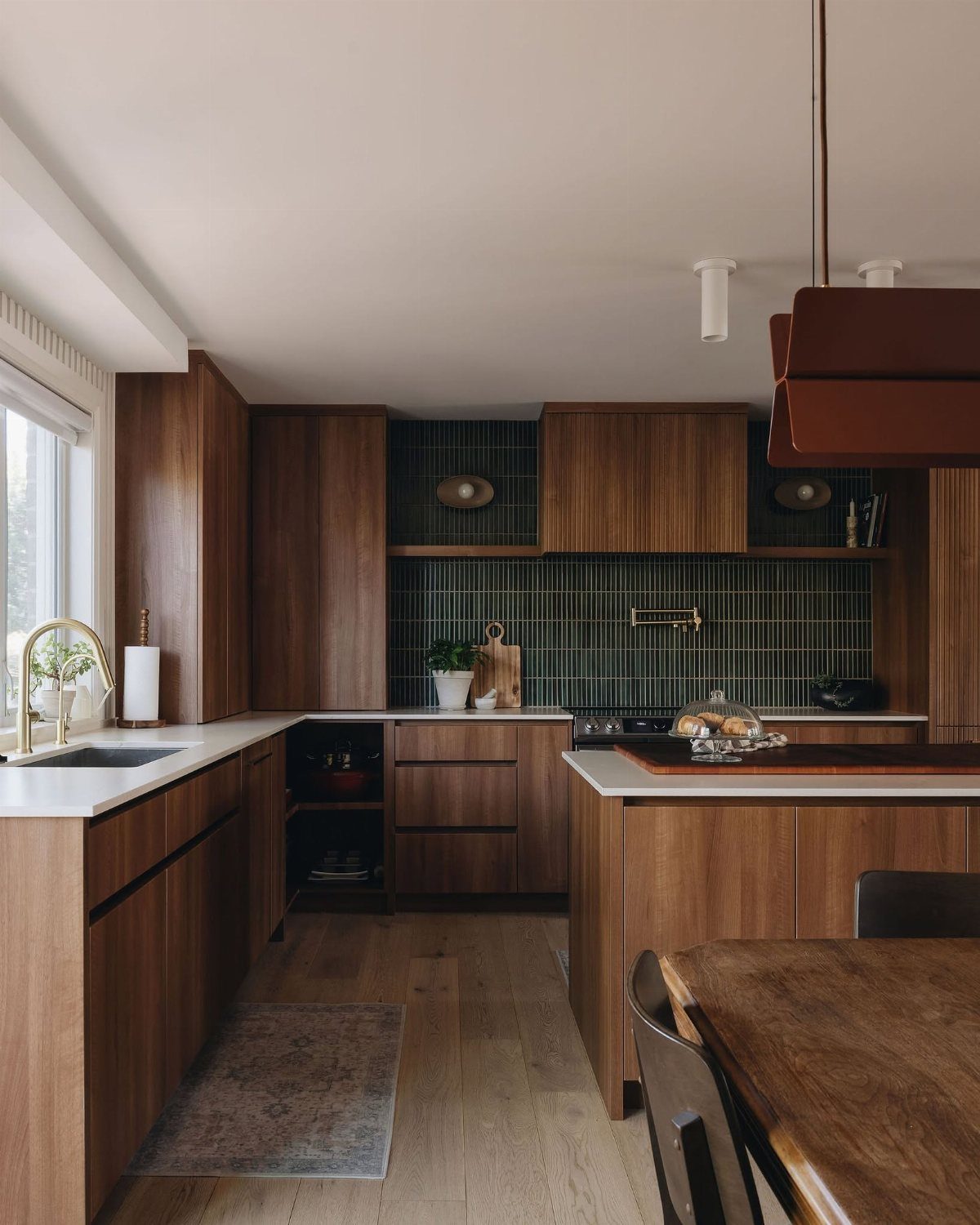 Mid century modern kitchen with wood cabinets, green tile backsplash, and white countertops.