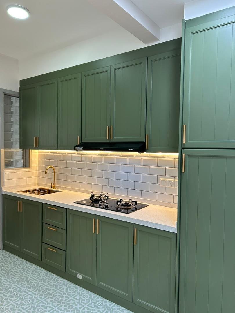 Olive green kitchen cabinets with gold hardware and white subway tile backsplash.