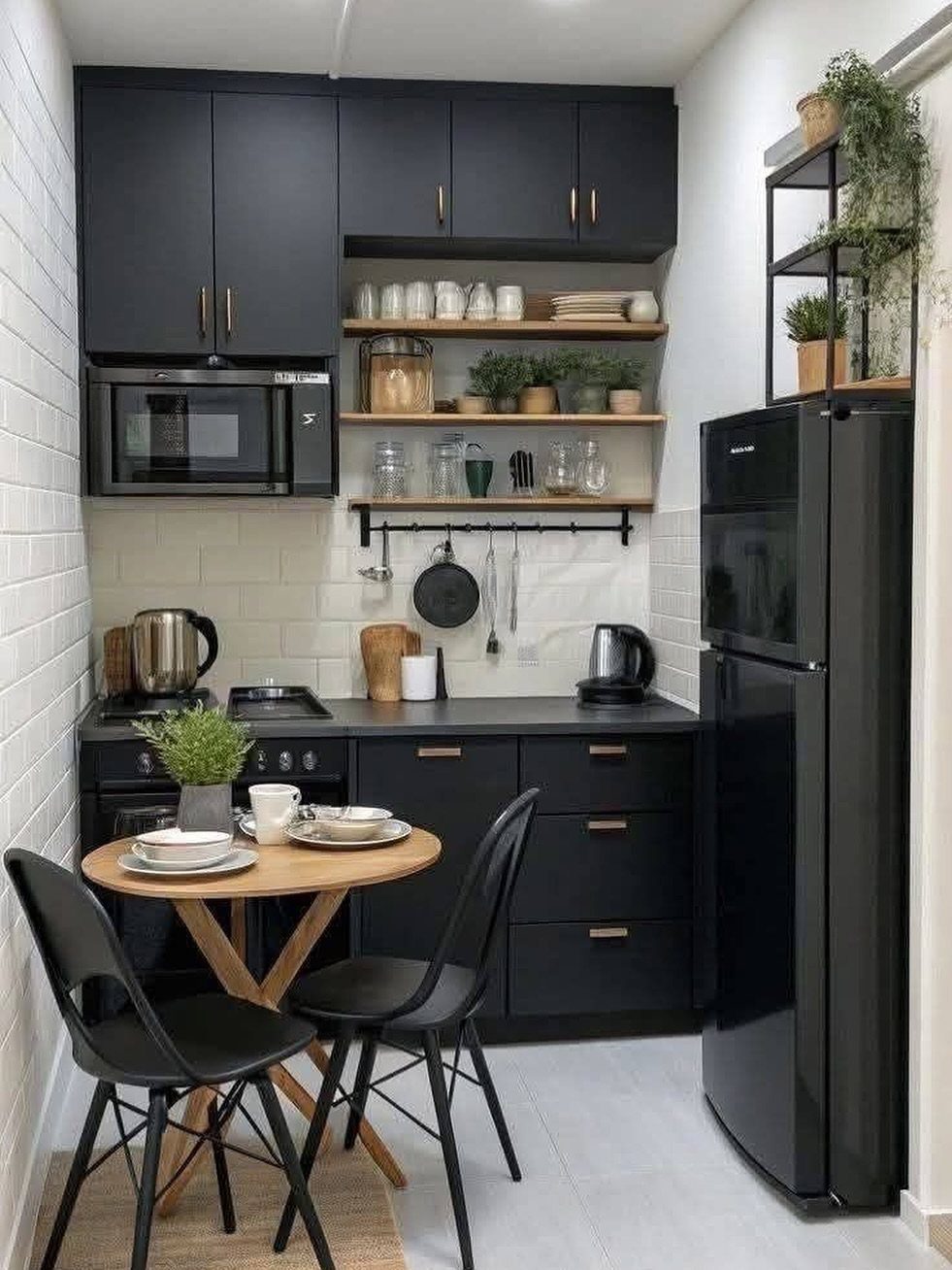 Small round wooden dining table with black chairs in a modern black kitchen