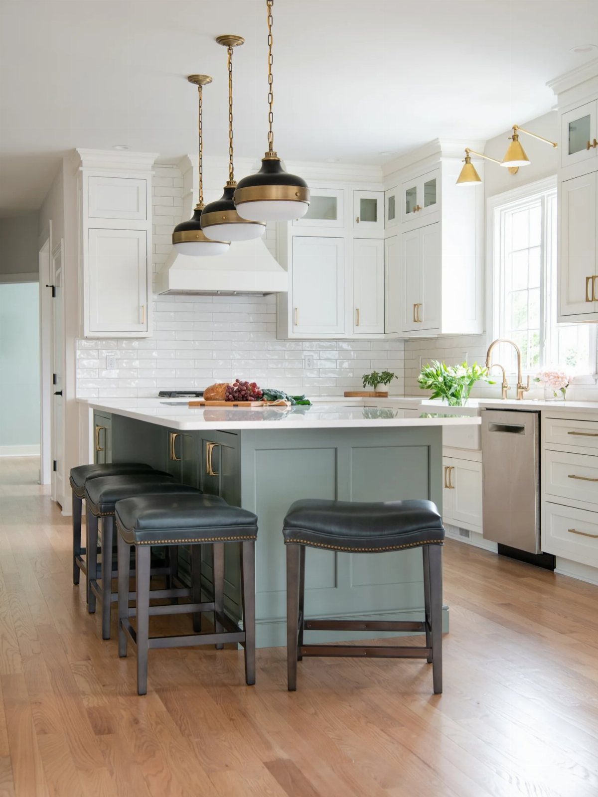 Mint green kitchen island with white upper cabinets and dark leather bar stools.