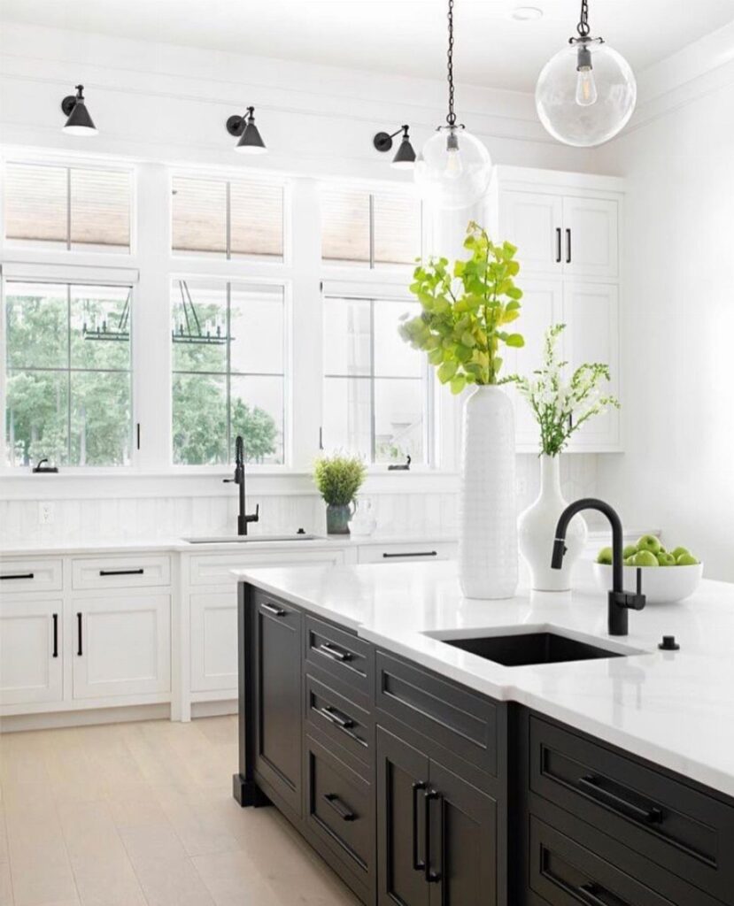 White kitchen cabinets and black island with matching black hardware and faucets.