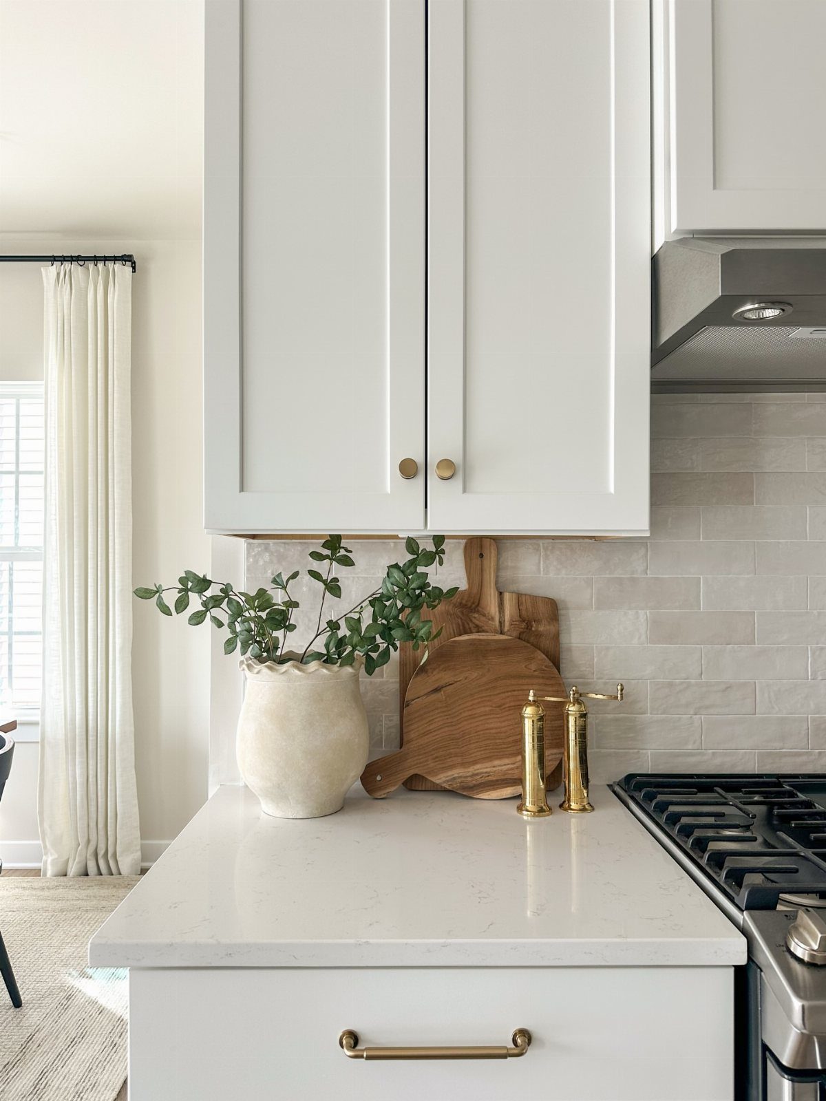 White subway tile backsplash in a bright kitchen with white cabinets and quartz counters.