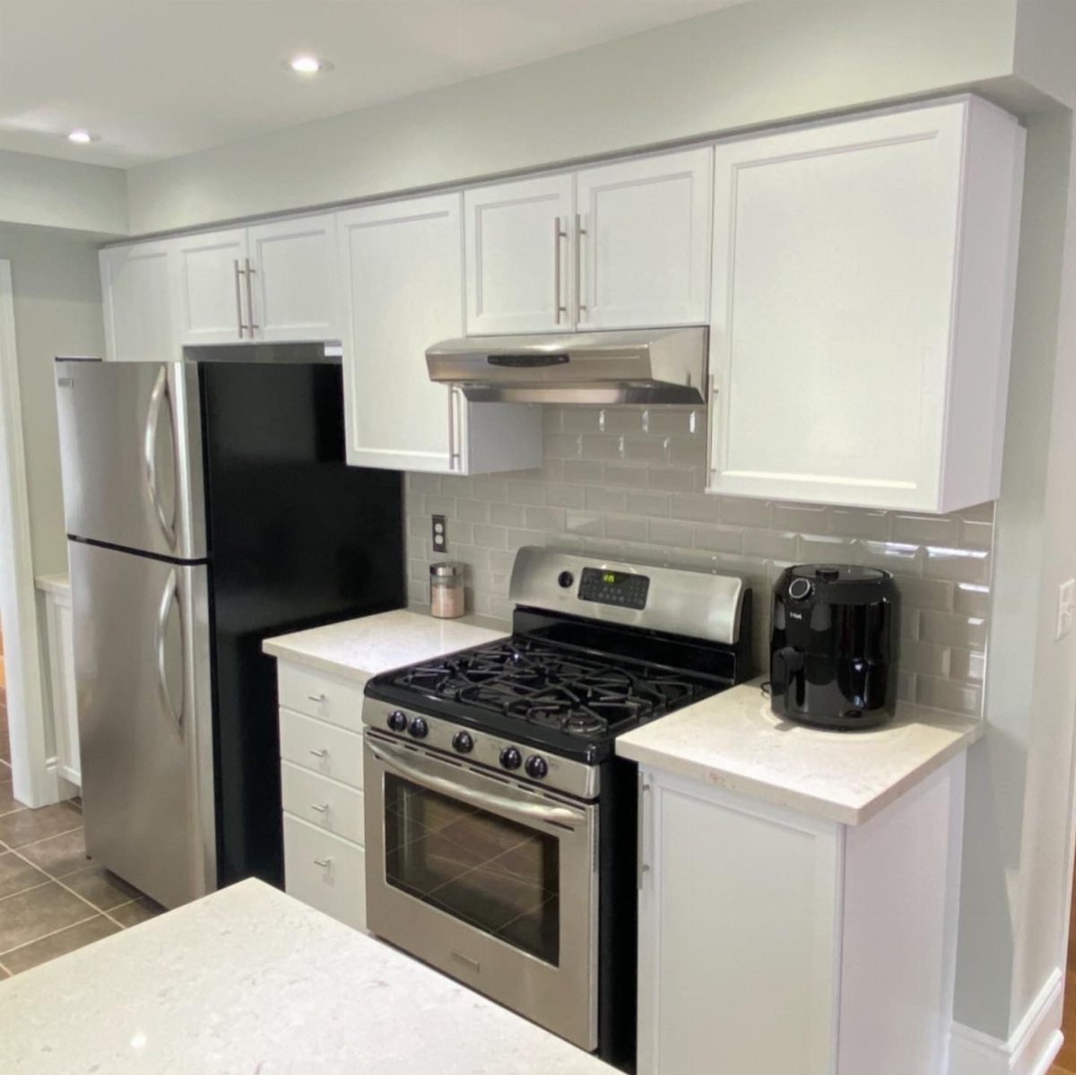 White kitchen cabinets and white walls with stainless steel appliances and white countertops.